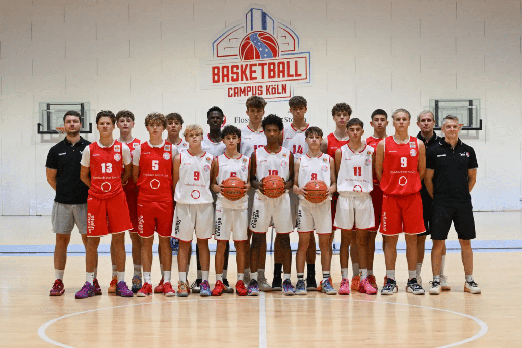 Basketballmannschaft RheinStars Köln posiert in Trainingskleidung in der Halle.