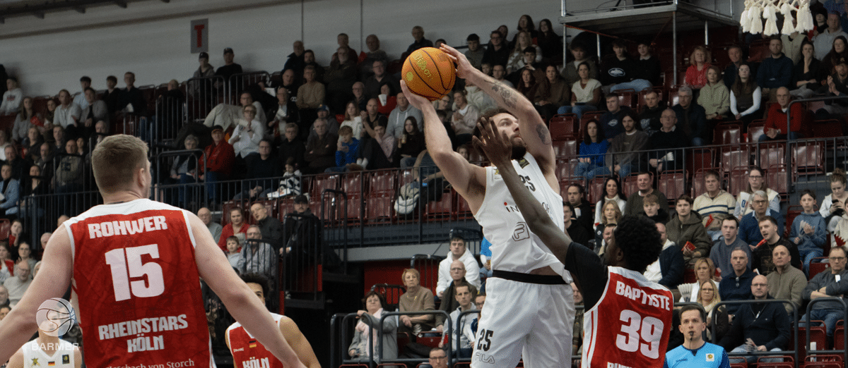 Basketballspieler der RheinStars Köln wirft Ball während Heimspiel vor Publikum.