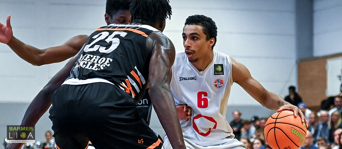 Basketballspieler der RheinStars Köln in weißem Trikot Nummer 6 dribbelt gegen Gegner in schwarzem Trikot.
