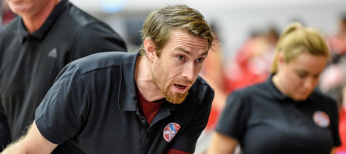 Mann in RheinStars-Köln-Polo spricht gestikulierend bei Sportveranstaltung.